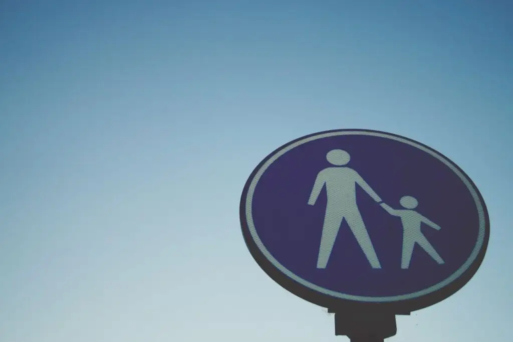 Zambian Business Compliance A close-up of a pedestrian crossing sign against a clear blue sky, symbolizing safety.