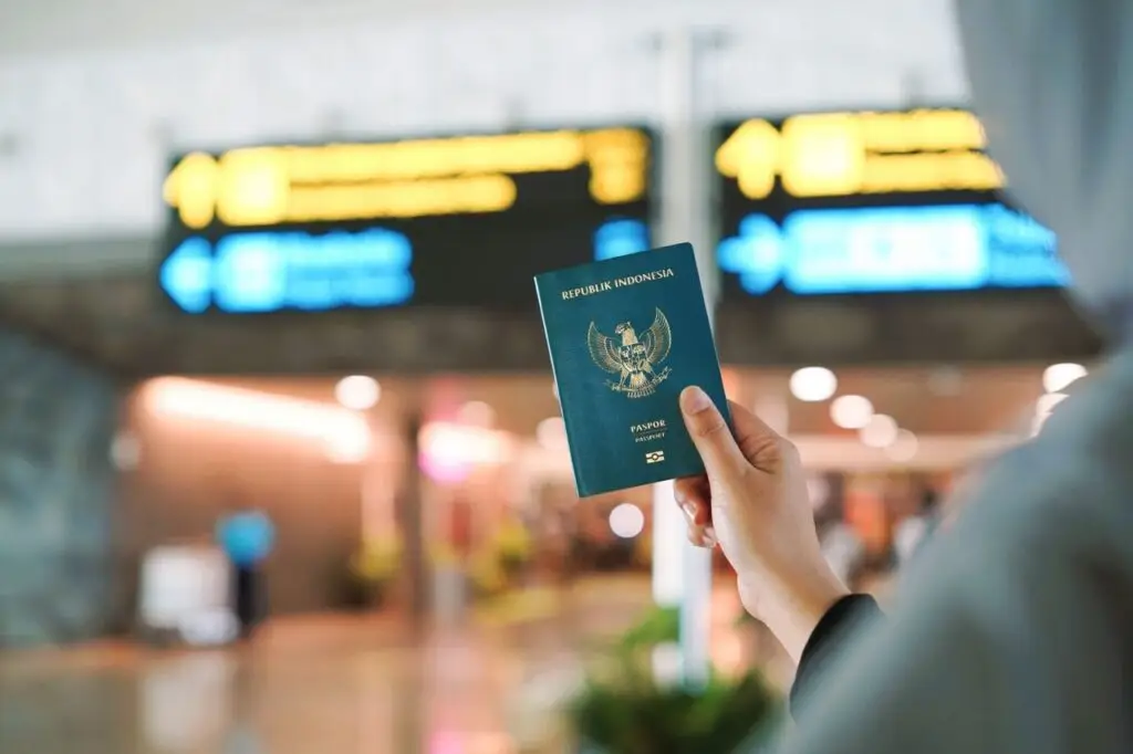 Moving to Zambia for Business A person holding an Indonesian passport at a busy airport terminal in Yogyakarta, Indonesia.