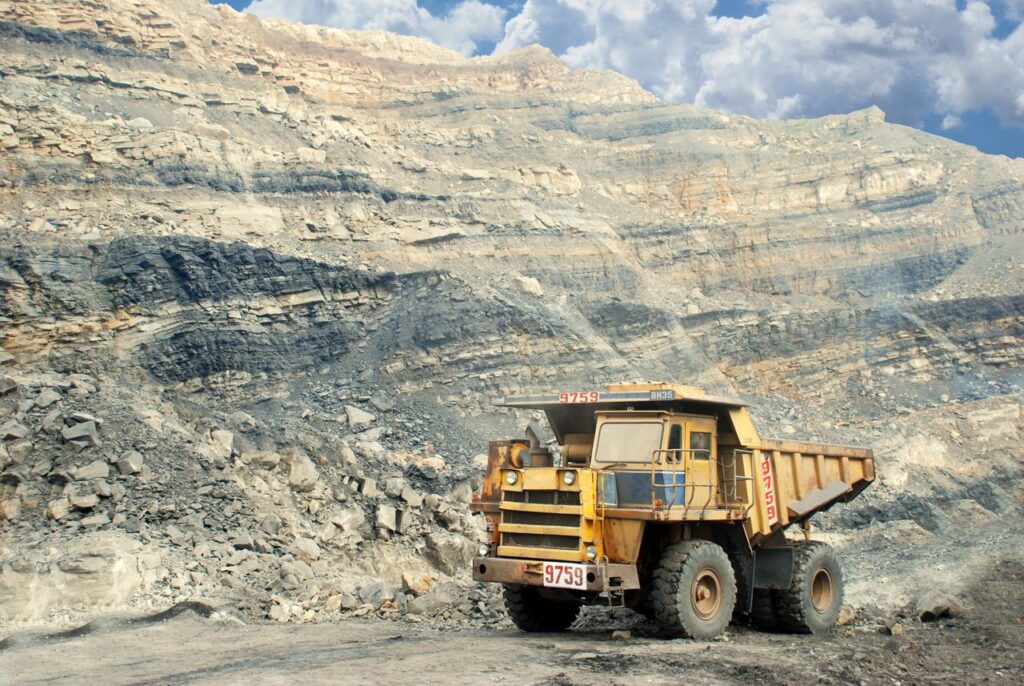 Zambia's Mining Sector A large yellow mining truck in a rocky quarry under a clear sky.