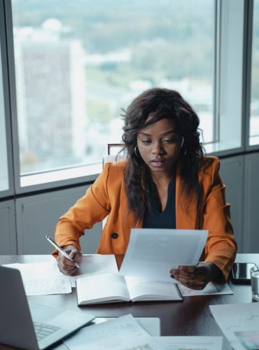 Professional woman in a bright office reviewing paperwork. Productivity and focus in a business setting.